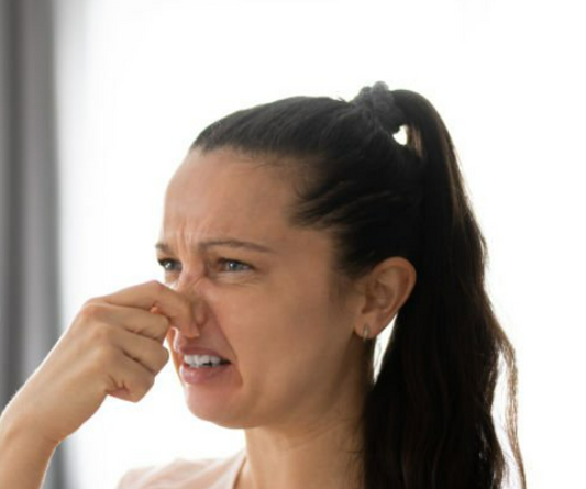 A person holding their nose due to a strong odor.