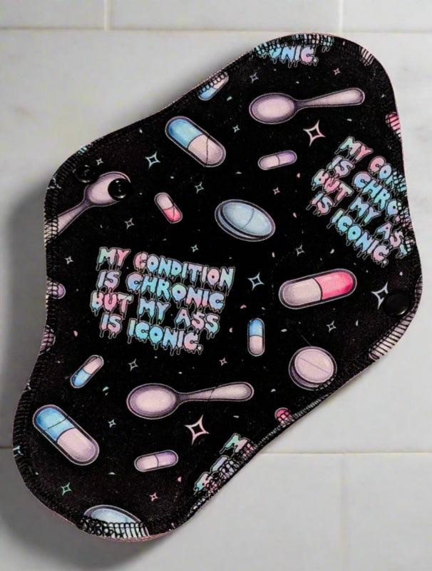 Black background with pills, spoons and stars with the words My condition is Chronic but my ass is iconic