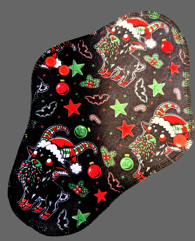 black Background witgh stars, bats, baubles and holy with goat with green and red horns, santa hat and red shoes eating boughes with holy 