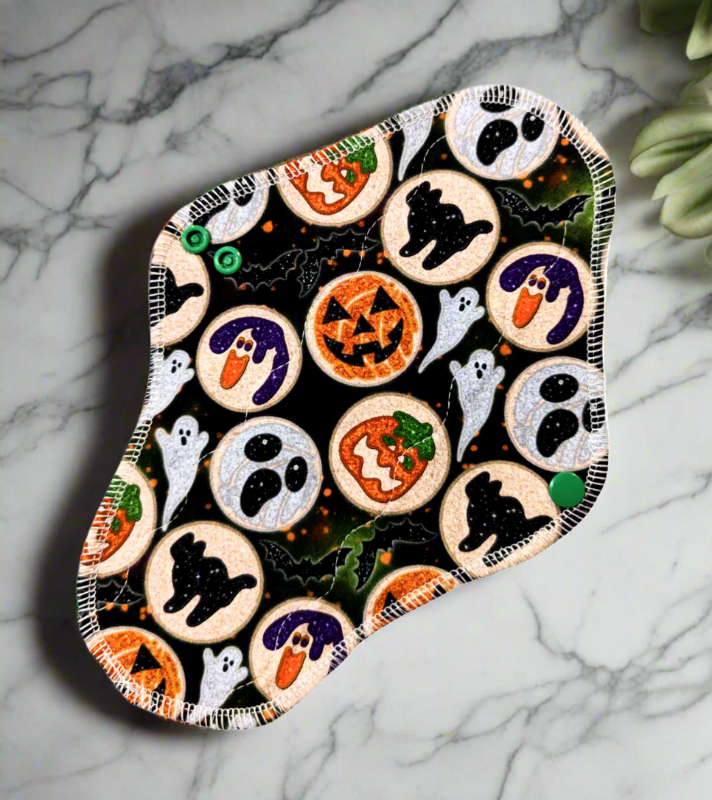 Black and green background round sugar cookies with different designs such as pumpkins, black cats and ghosts